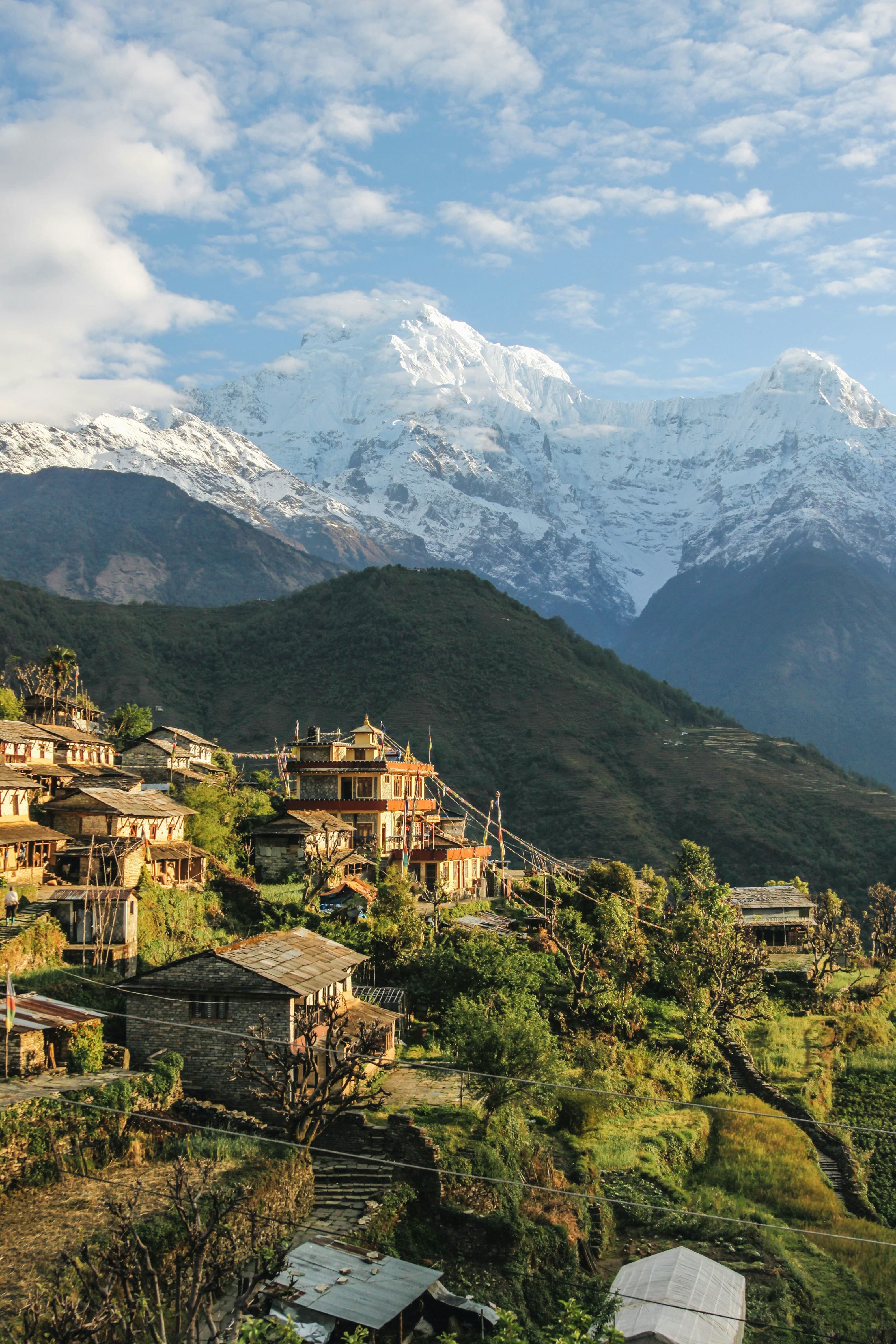 A Gurung village of stone houses on terraced hillside below the snow peaks of Annapurna South and Hiunchuli