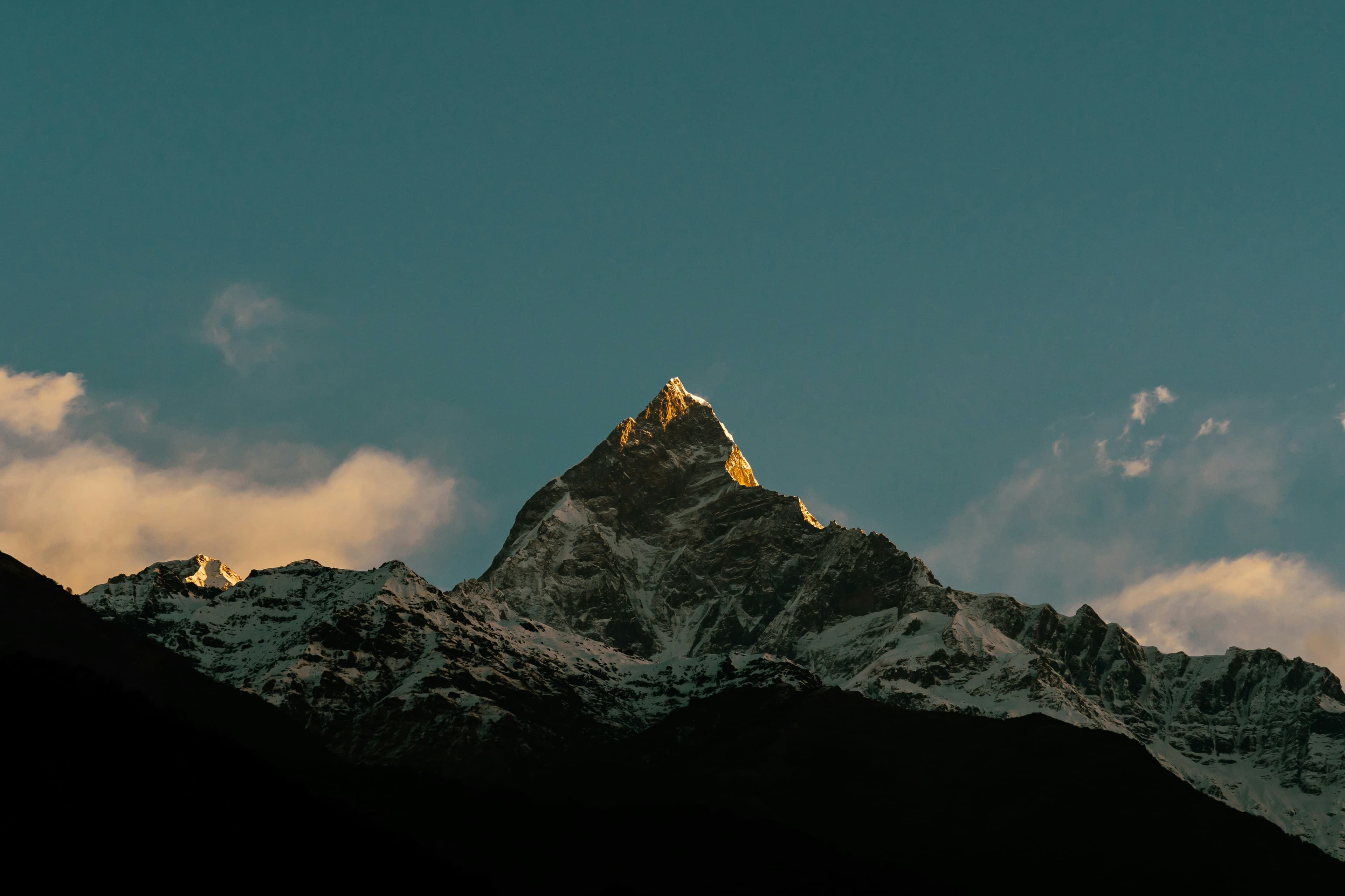 First light on the summit of Machhapuchhre, the Fishtail peak, above a dark ridge