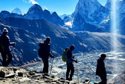 four trekkers, holding walking poles descending to Gokyo Valley with Tabuche Peak on the backdrop